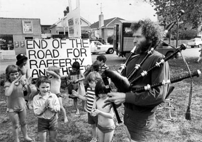 A teacher playing the bagpipes and small dancing children from the Fitzroy Community School join in the anti-freeway protest on the median strip of Alexandra Parade